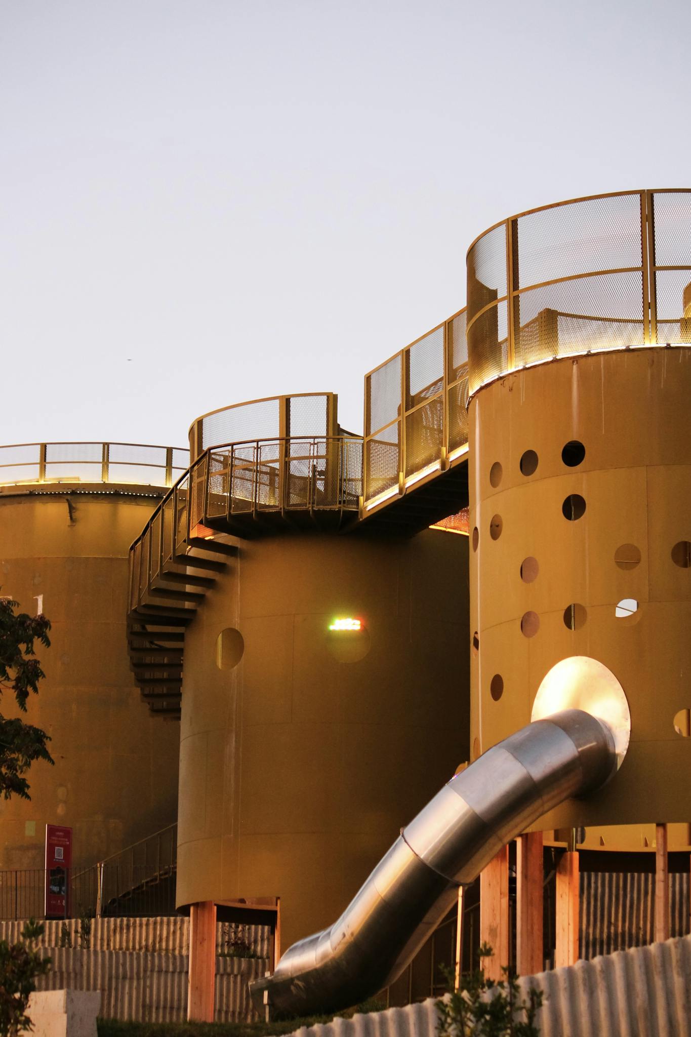 Yellow cylindrical structures with slides under evening light.